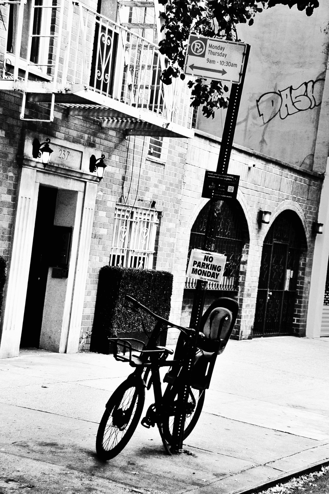 bicycle locked to pole that says no parking monday