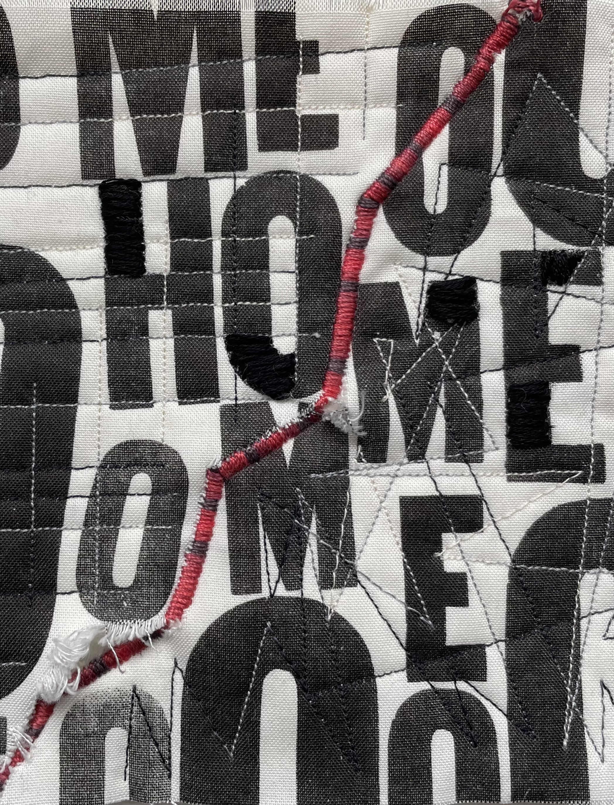 quilt printed with letters that make up the word home and a crooked red line
        			stitched between ho and me
