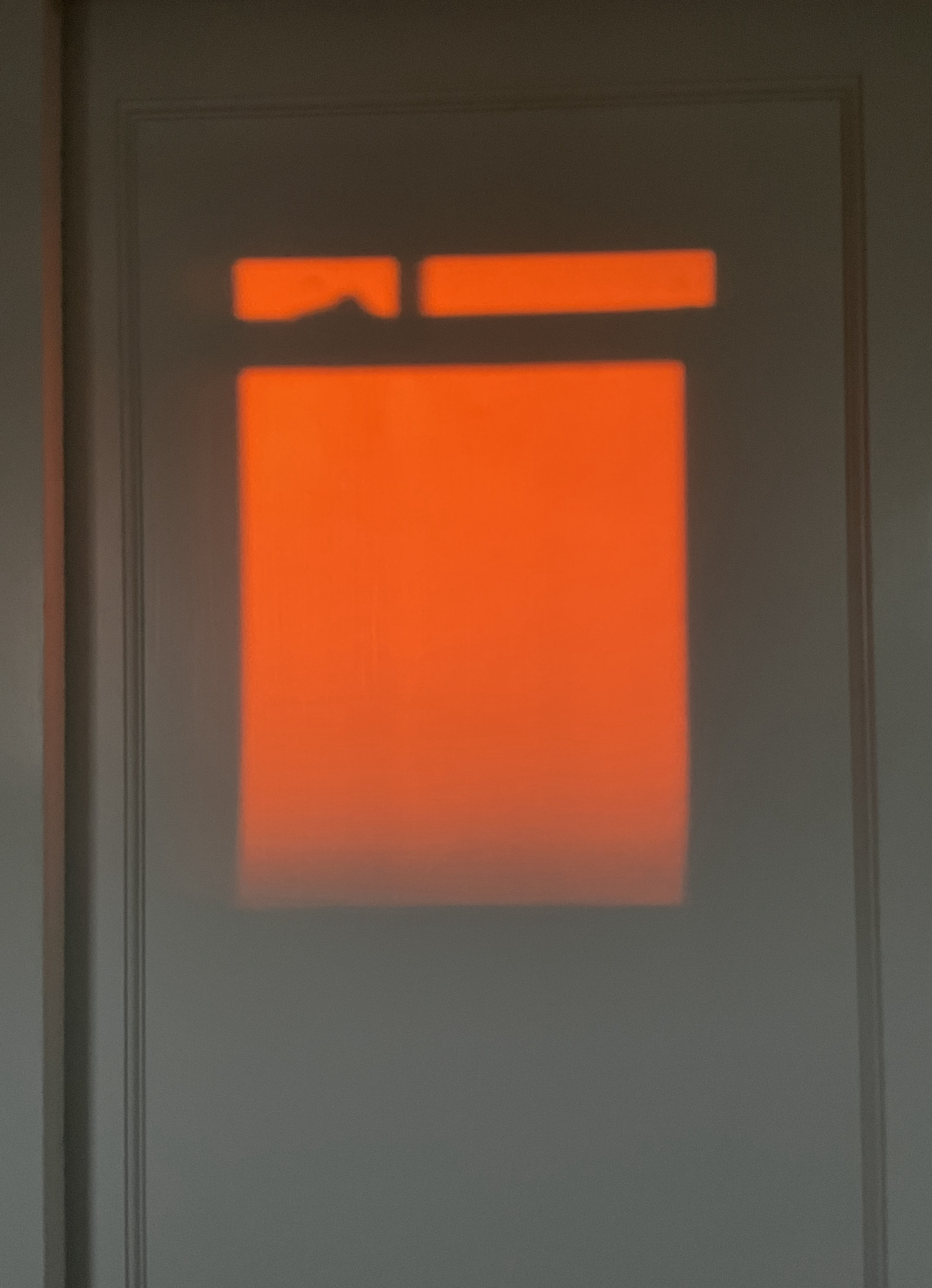 red shadow of a window on the wall from a sunset