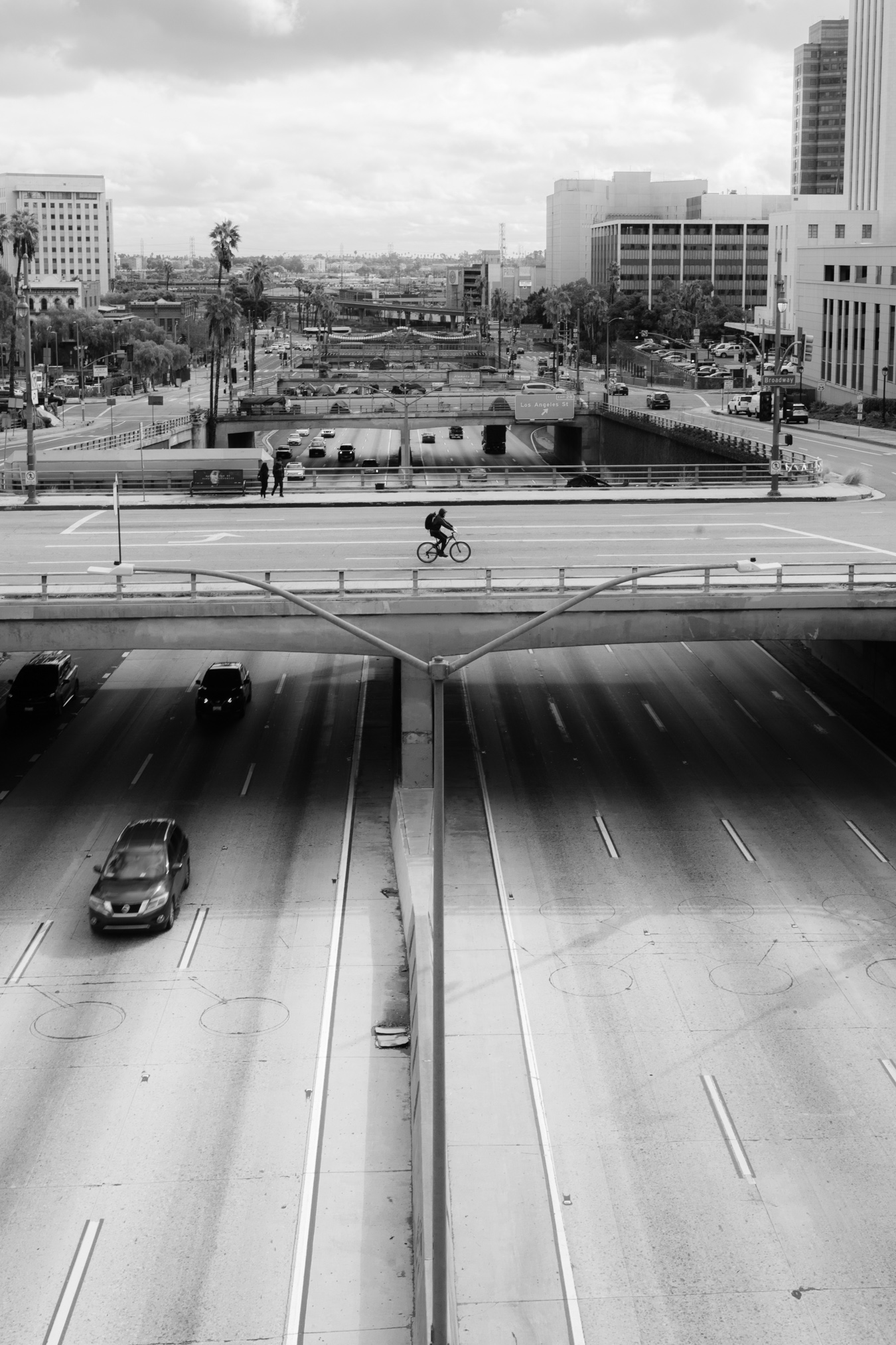 city with bicycle riding on overpass over freeway with cars