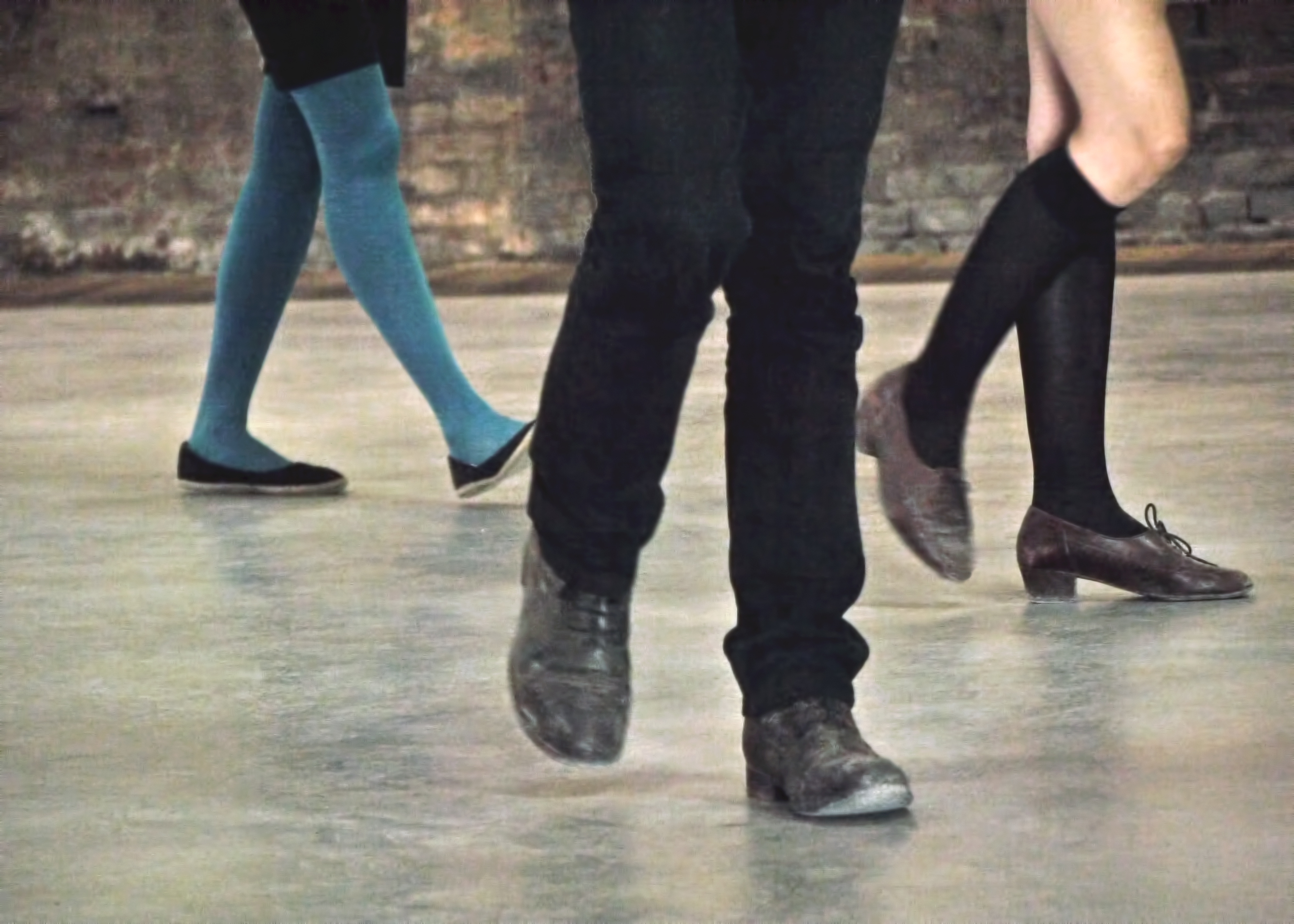 photograph of three pairs of legs walking on a street particularly one with long blue tights